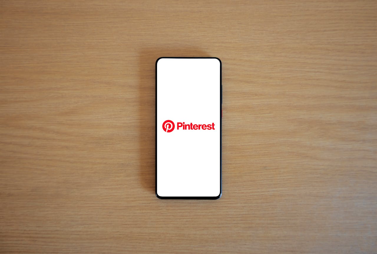 services-02 Smartphone with Pinterest logo on screen placed on a wooden surface, minimalistic tech concept.