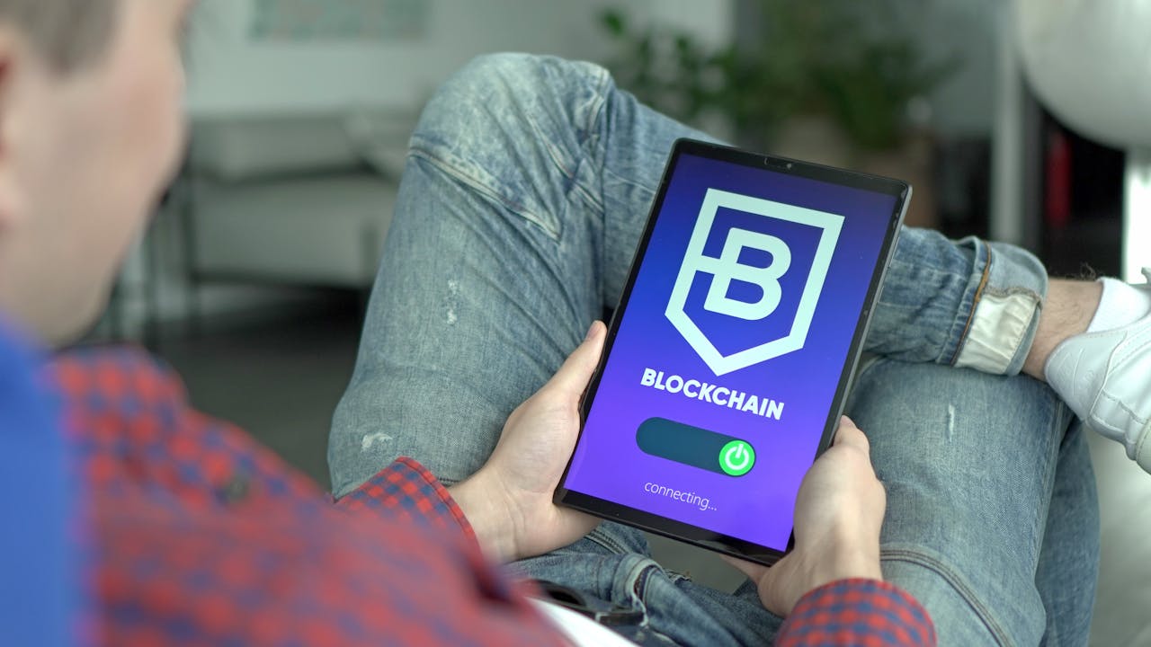 gallery-1 Adult holding a digital tablet displaying a blockchain application interface.